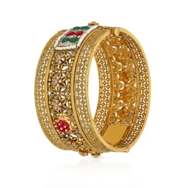 Intricately designed gold bangle with red and green embellishments.