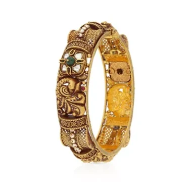 Intricately designed gold bangle adorned with green gemstones and intricate patterns.