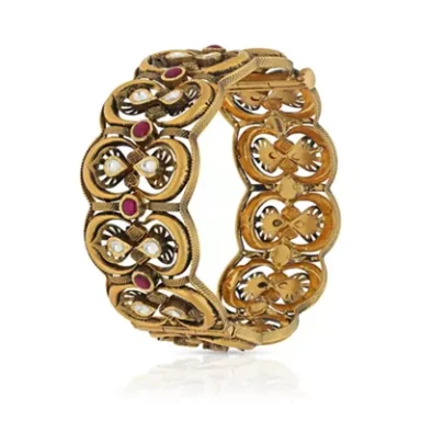 Gold bracelet with intricate designs, pearls, and ruby embellishments.
