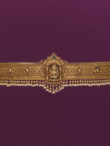 Ornate gold belt decorated with intricate designs and a central pendant.
