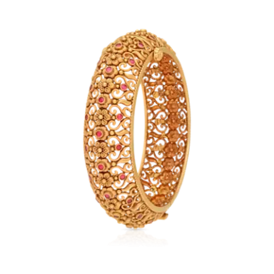 Intricately designed golden bangle with floral patterns and pink gemstone accents.