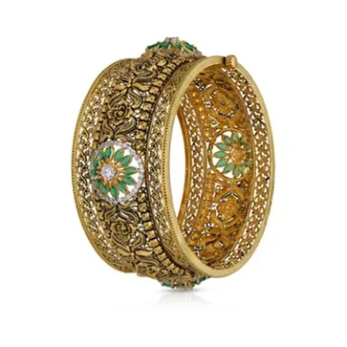 Intricately designed gold bangle with floral motifs and green embellishments.