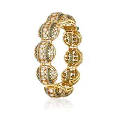 Gold decorative bracelet with intricate filigree design and green accents.